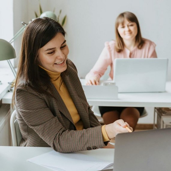 Two individuals in office, one with laptop