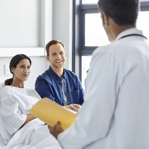 Couple sitting in hospital bed listening to Doctors prognosis, woman is the patient 