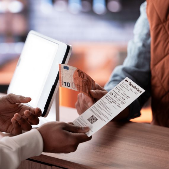 Two individuals at a table, one displaying a smartphone and the other holding a paper ticket with a QR code