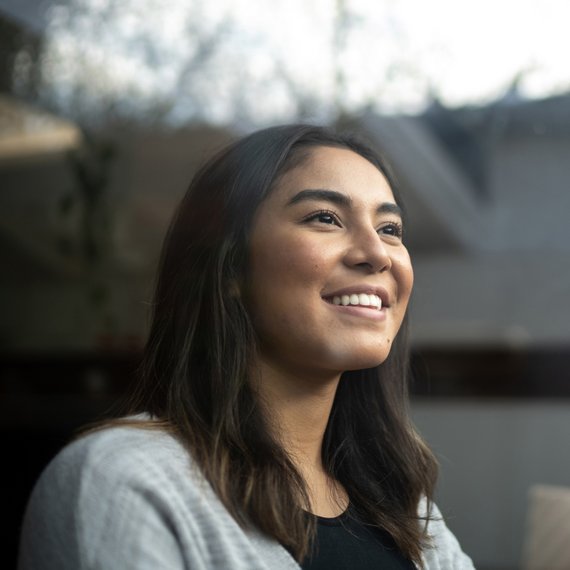 Person in light-colored top indoors, window reflection