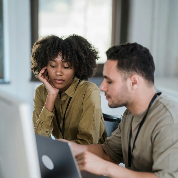 Two individuals at desk with laptops