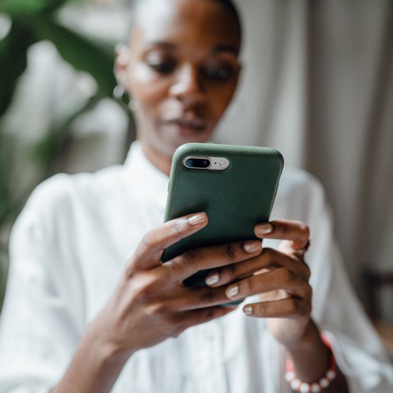 Person holding smartphone with green case, white shirt