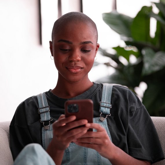 Person in overalls using smartphone