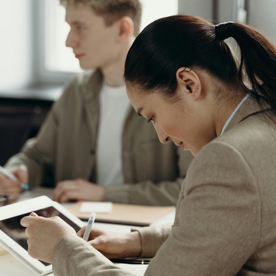 Two individuals at table, one taking notes