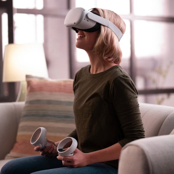 Individual on couch wearing VR headset and holding controllers