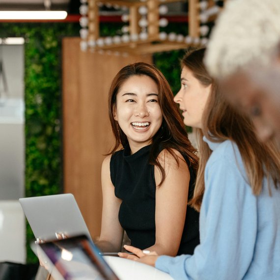 Two individuals at a table, one with laptop