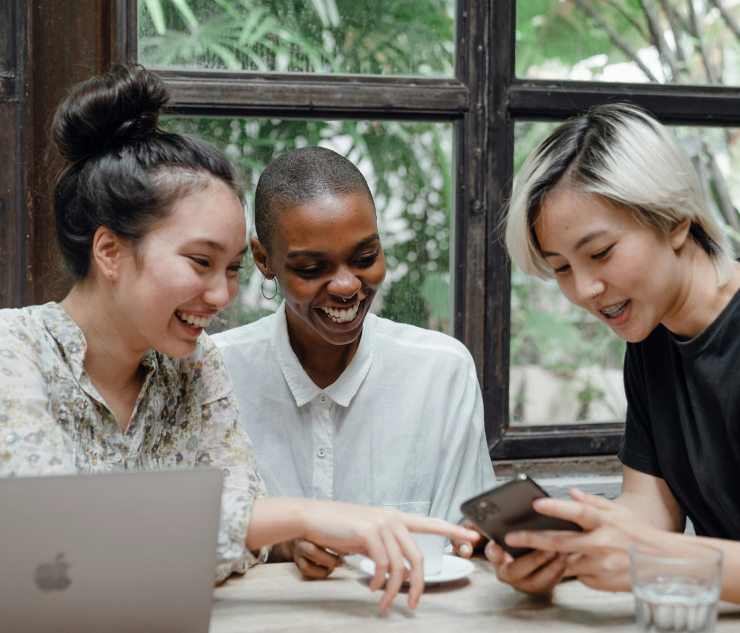 Three individuals at table with laptop, mobile phone
