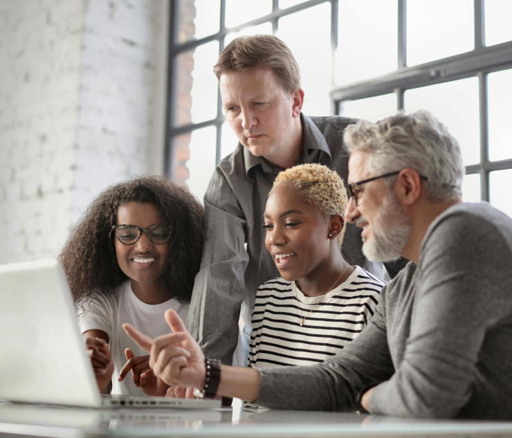 Group of four individuals around laptop