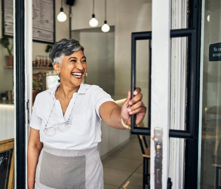 Individual holding door open at cafe entrance