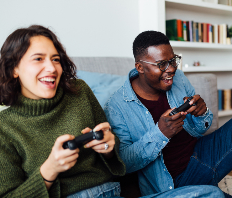 Two people on couch playing video games with controllers