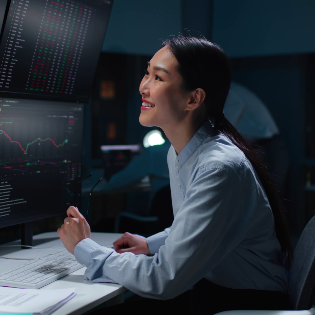 Individual at computer with multiple monitors, professional data analysis setting