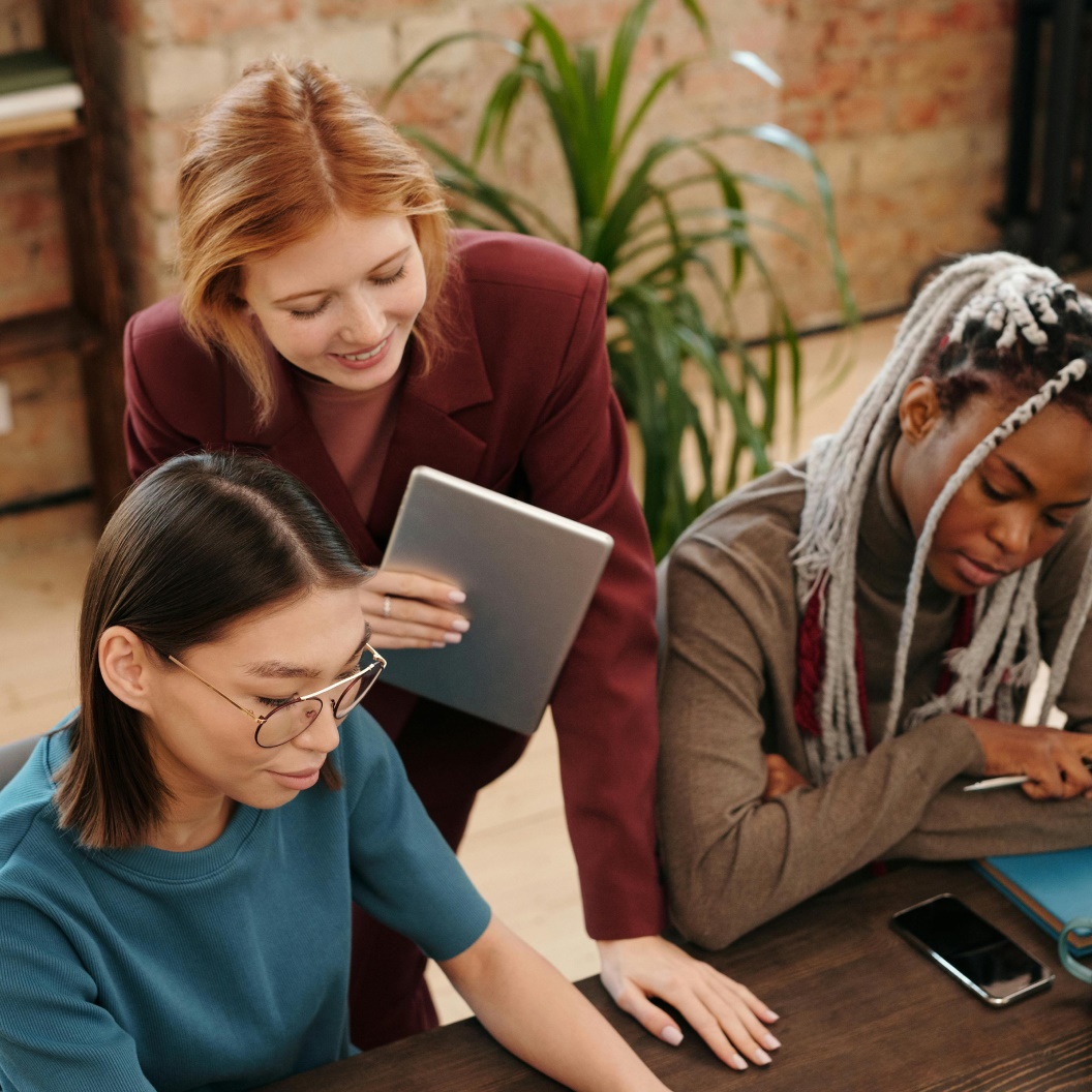 Three individuals at table with tablet, smartphone, and papers