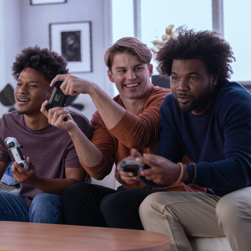 Three people on couch playing video games with controllers