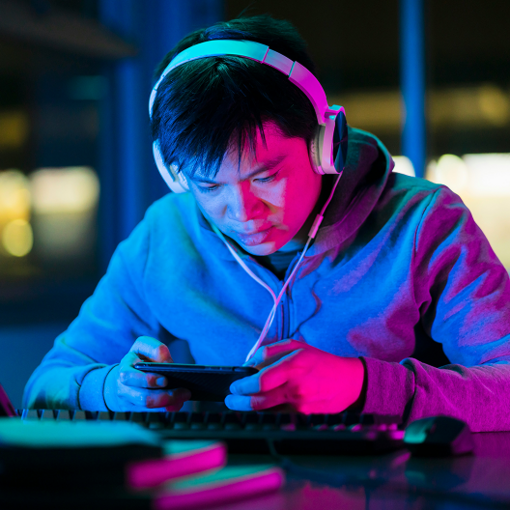 a man with headphones, focused on his smartphone screen