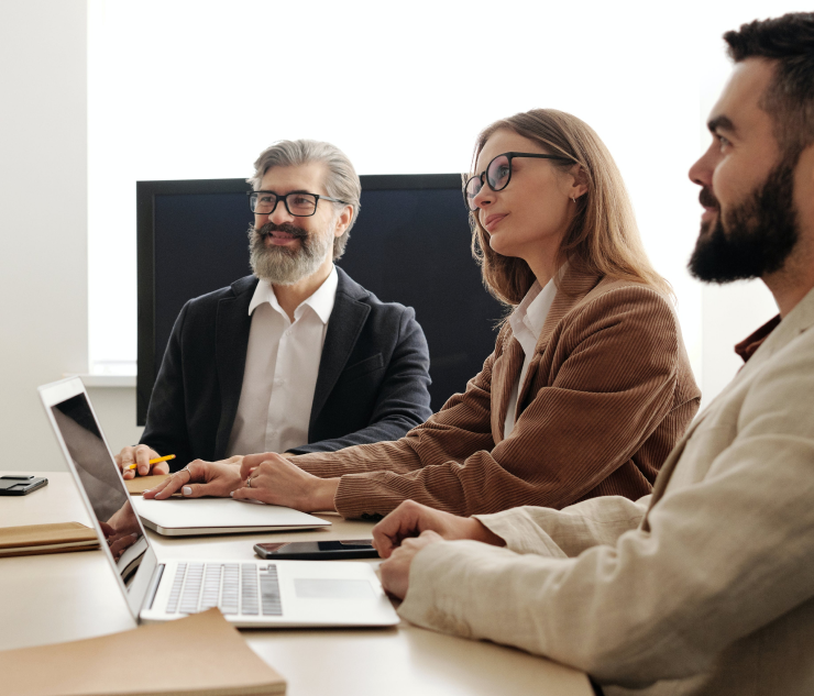 Three individuals at table facing laptop