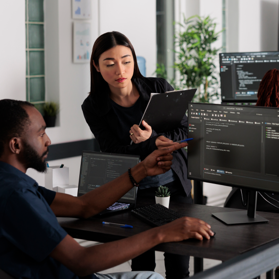 Two professionals working with computer and clipboard in office